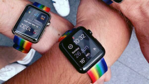 A picture of two wrists, both displaying the rainbow themed straps that Apple made available to celebrate Pride